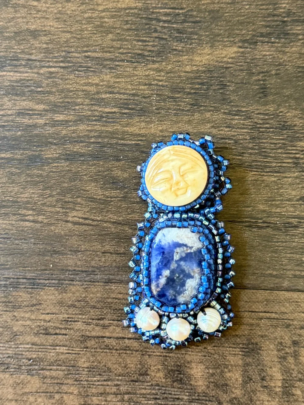 hand-beaded artisan brooch with moon face